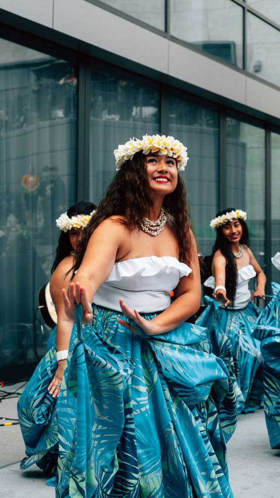 Young girl dancing hula next to a wall.